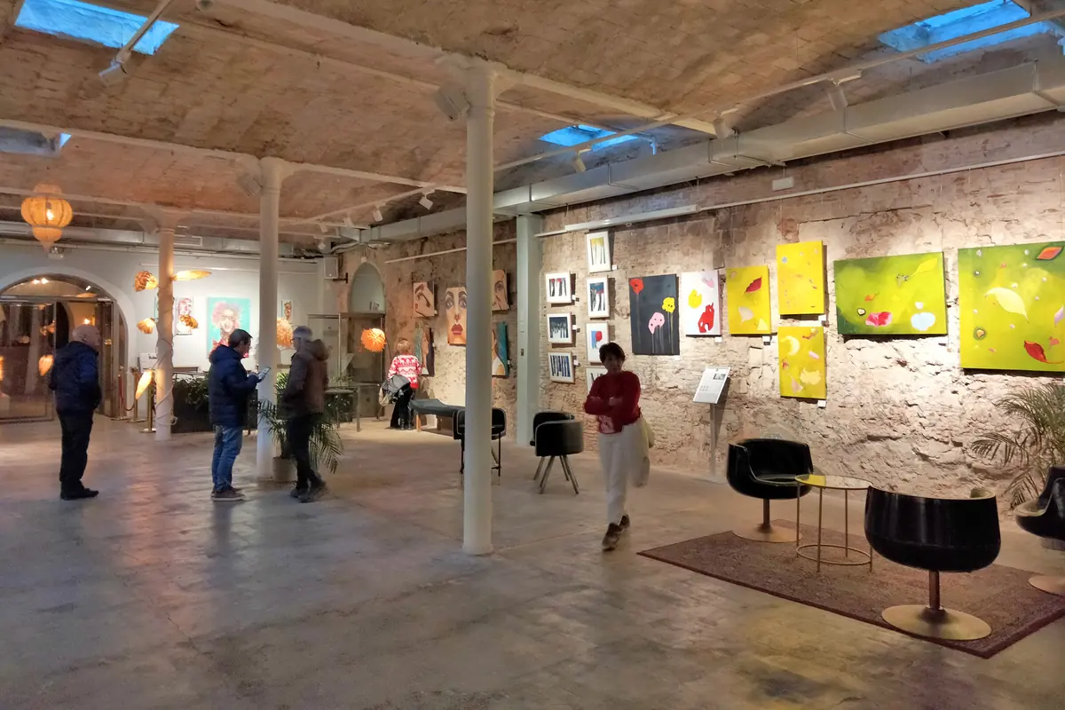 Besucher betrachten Gemälde an den Wänden eines Galerieraums mit Gewölbedecke und Oberlichtern