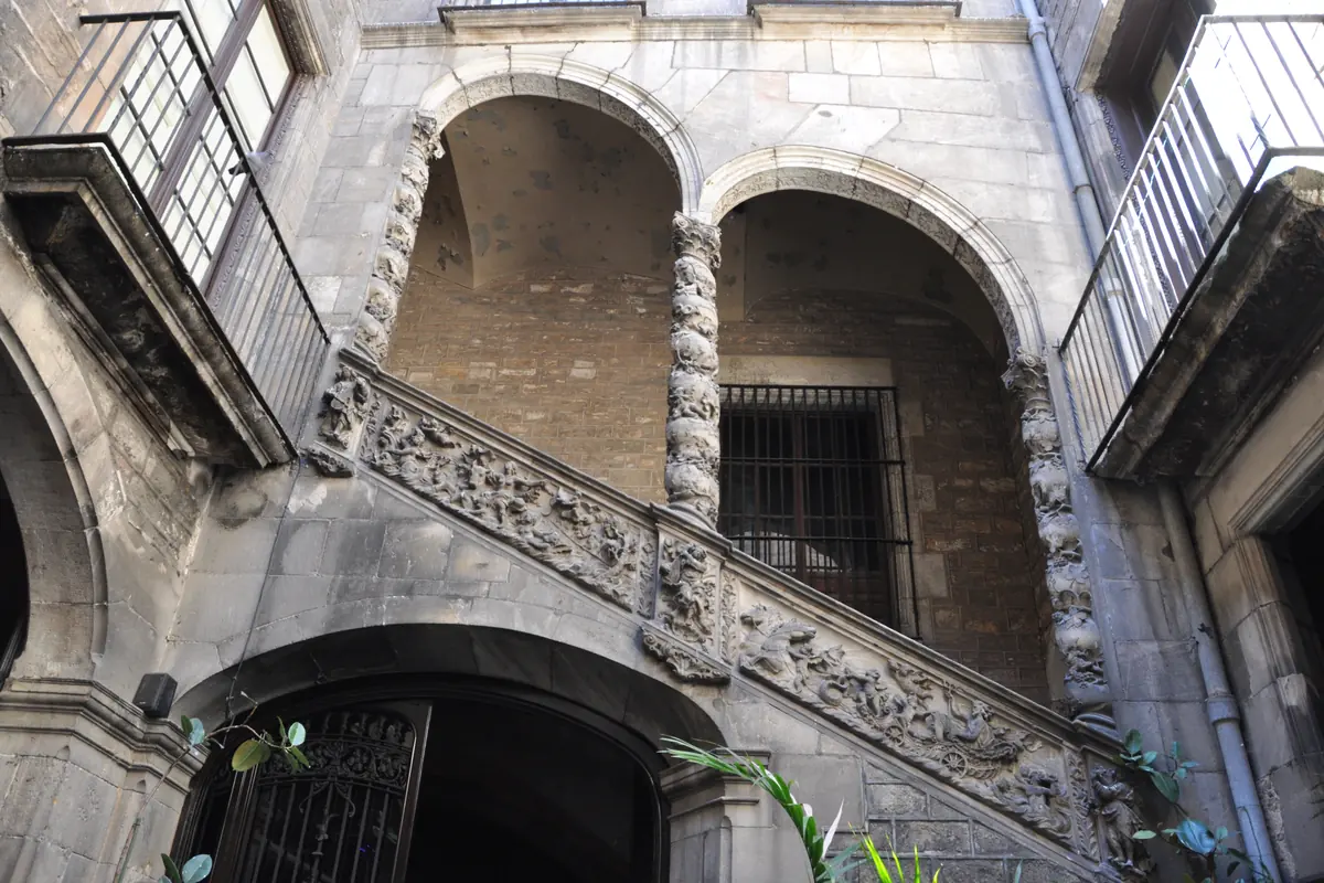 Die steinerne Treppe des Palau Dalmases, die sich unter zwei ansteigenden Bögen auf gedrehten Säulen mit geschnitztem Geländer erhebt